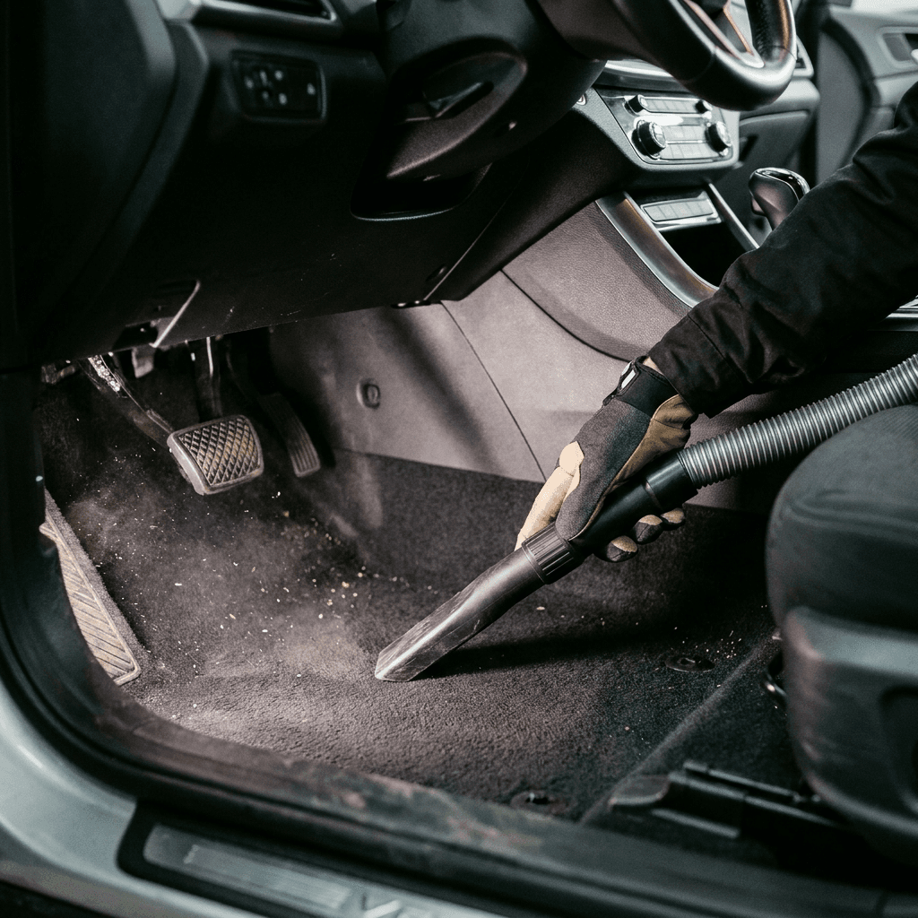 Detailer using a drill brush on a car carpet