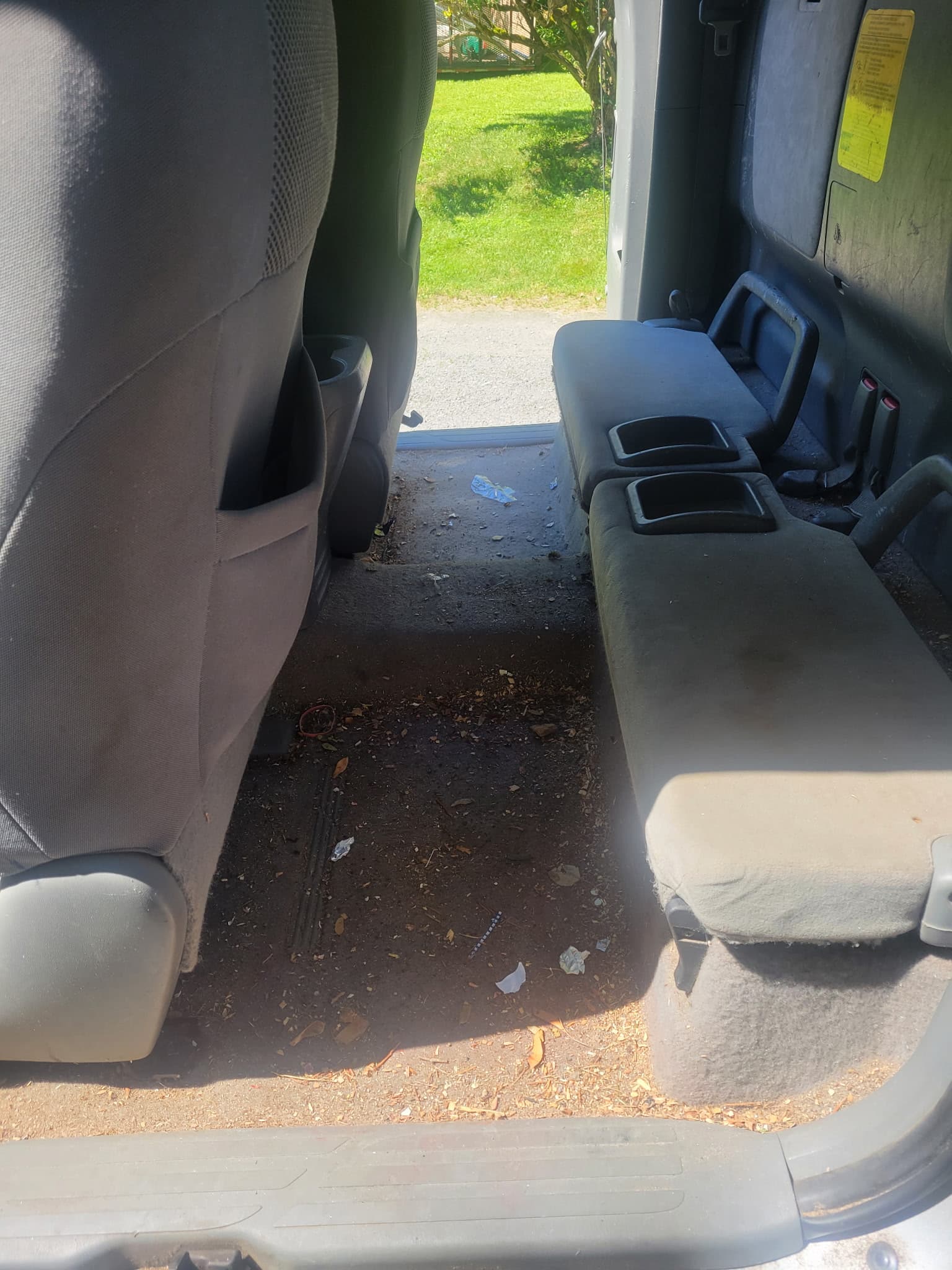 Dirty truck interior showing a floor covered in leaves, dirt, and scattered trash items.