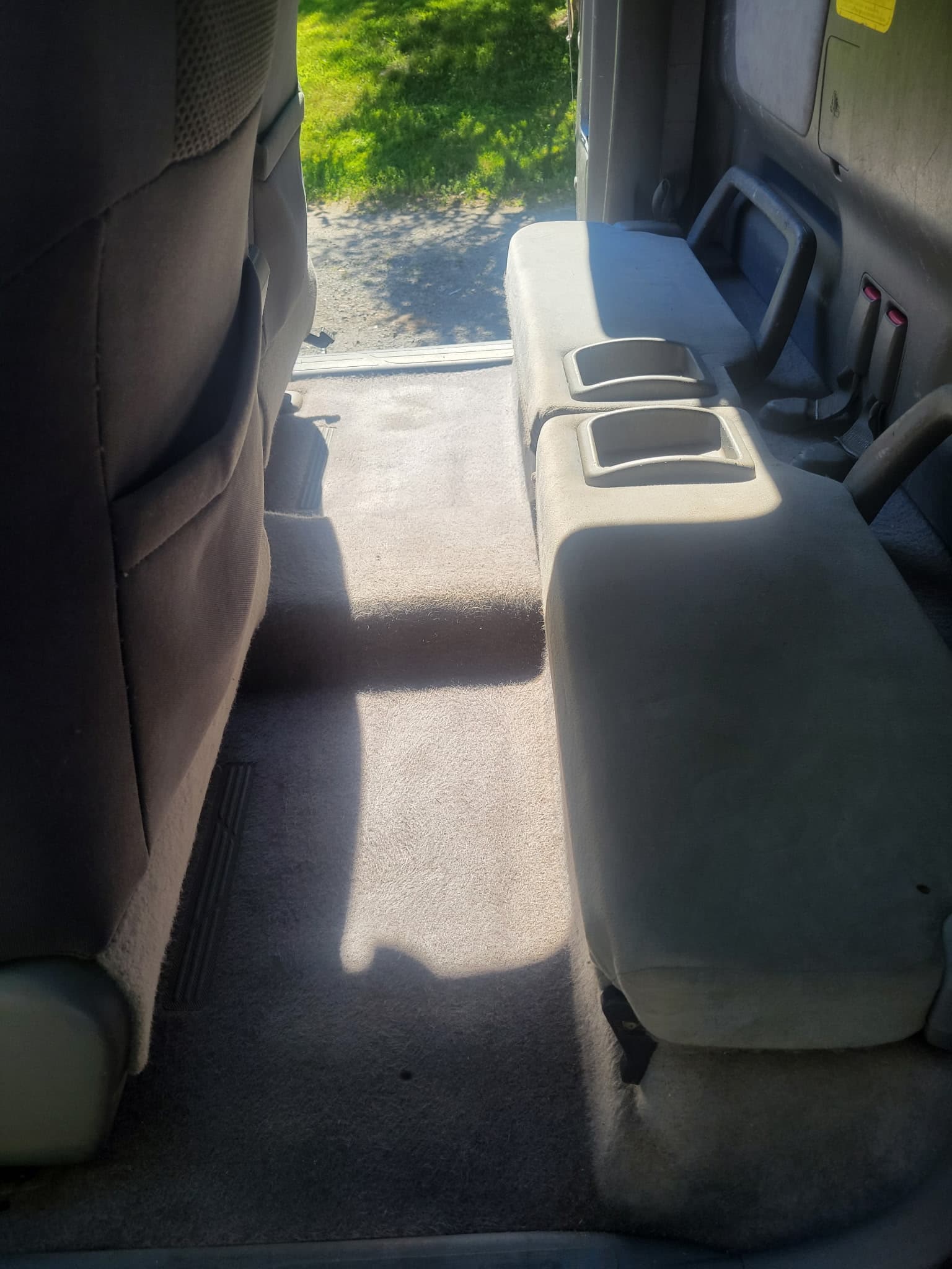 Gray carpeted truck interior showing the rear bench seat with two integrated cup holders.