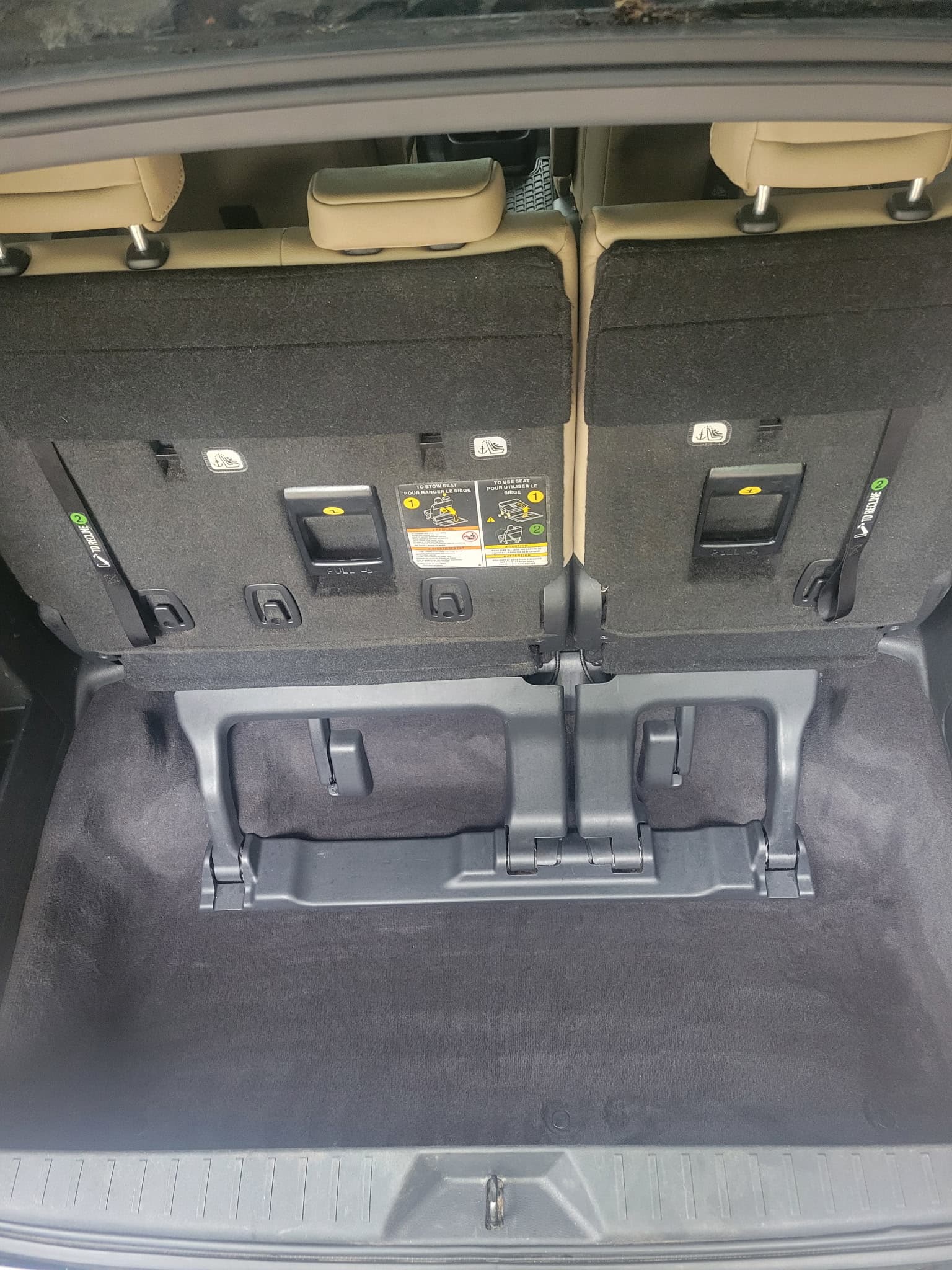 Upright third-row seats in a car's trunk with a deep carpeted storage well.